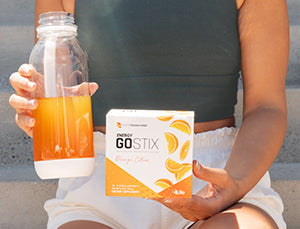 Woman holding a water bottle and a box of 4Life Energy Go Stix Orange Citrus